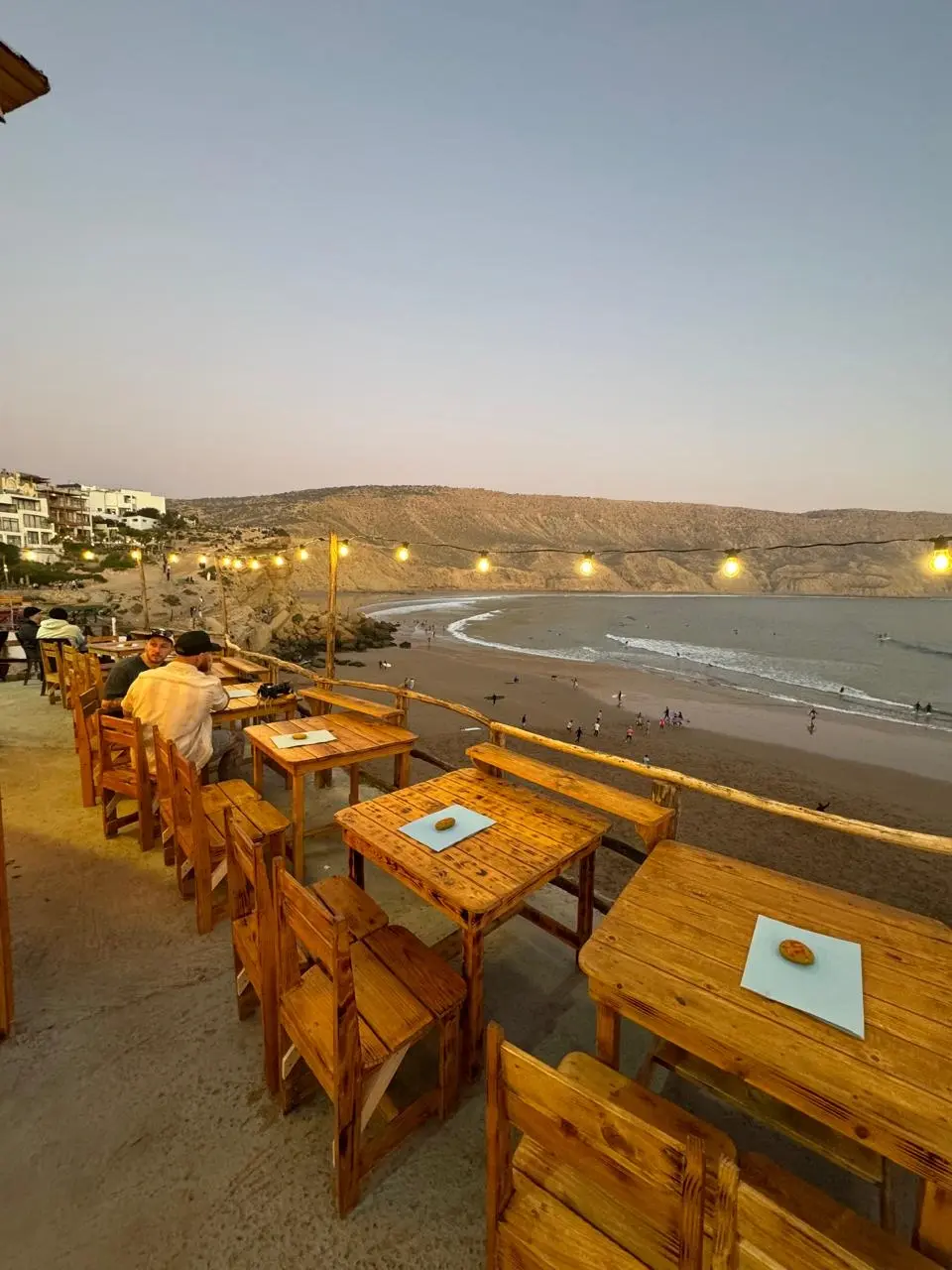 Lina House rooftop Imsouane Morocco — wooden terrace at sunset overlooking Magic Bay surfers